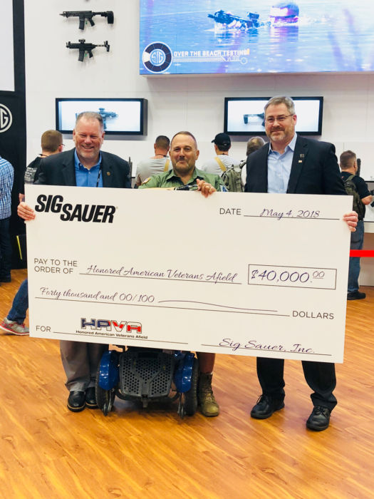 SIG SAUER and HAVA representatives stand with giant check of $40,000 donated
