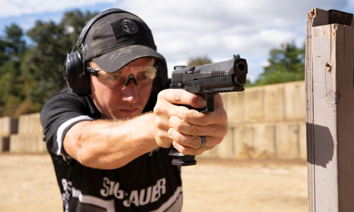 Team SIG member Daniel Horner aims his P320 XFIVE pistol with iron sights