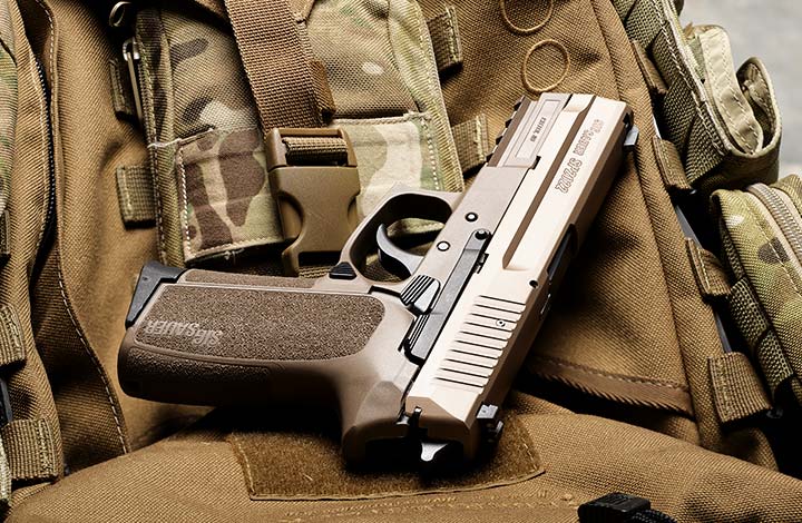 The SIG P2022 pistol in coyote tan resting on a camo pack.