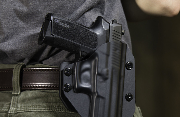 Black polymer SIG P2022 pistol holstered in waist belt holster gear.