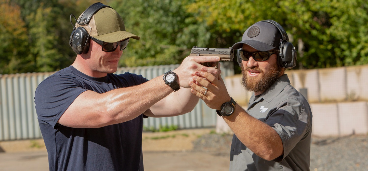 Academy instructor provides individual instruction to client for handling of a pistol. 