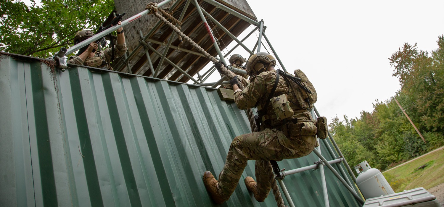 Academy students ascend climbing wall to promote professional training techniques. 